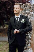 Portrait of a handsome young groom on an autumn day outdoors in an elegant suit. Outdoor photo. Handsome man in a business suit. photo