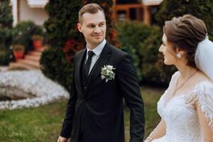 un Boda Pareja es caminando en naturaleza en un otoño día. contento joven novia y elegante novio participación manos. un elegante Pareja de recién casados en su Boda día. foto