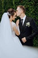 A young bride and groom tenderly embrace in the rays of the autumn sun. Tender and beautiful young girl bride. A man kisses his beloved. Against the background of a beautiful garden photo