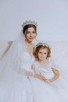 Portrait of the bride with her little sister in the room. Tender and sweet photo of a beautiful bride with her little sister.