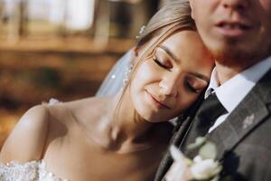 Portrait of a smiling bride with a bouquet of flowers, embracing her husband, with her eyes closed. Nice wedding celebration. Wedding hairstyle with a veil. Couple in love. photo