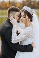 un joven novia y novio tiernamente abrazo en el rayos de el otoño Dom. oferta y hermosa joven niña novia. un hombre Besos su amado. en contra el antecedentes de un hermosa jardín foto