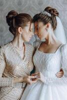 A beautiful and happy mother and her daughter, the bride, are standing next to each other. The best day for parents. Tender moments at the wedding. photo