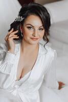 portrait of an incredibly beautiful girl bride in a white robe in the bedroom, the bride poses in the morning before the wedding ceremony. photo