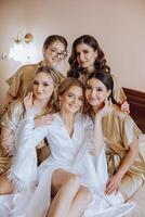 Portrait of the bride with her friends. Elegant and stylish bride with her friends in matching dresses in the room in the morning. Many beautiful girls in one photo. photo