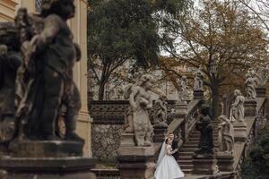 un encantador novia en un maravilloso vestido, un largo velo, abraza el novio en un negro traje. un Boda Pareja en el ciudad centrar en el escaleras. foto