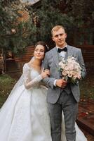 Handsome groom and charming bride together in the park. Portrait. Luxurious dress with a long train. She put her arm around him. Elegant young groom. Wedding bouquet. luxury wedding photo