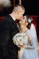 A young bride and groom tenderly embrace in the rays of the autumn sun. Tender and beautiful young girl bride. A man kisses his beloved. Against the background of a beautiful garden photo