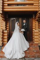 Handsome groom and charming bride stay together near modern wooden house in park photo