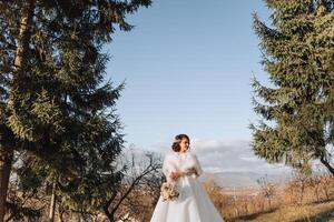 Portrait. A brunette bride in a dress and a veil, with a chic crown, poses with a bouquet. Silver jewelry. Beautiful makeup and hair. Autumn wedding. celebration photo