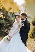 un joven novia y novio tiernamente abrazo en el rayos de el otoño Dom. oferta y hermosa joven niña novia. un hombre Besos su amado. en contra el antecedentes de un hermosa jardín foto