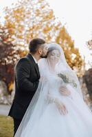 Wedding couple on a walk in the autumn park. The bride in a beautiful white dress. Love and relationship concept. Groom and bride in nature outdoors photo