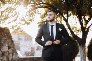 Portrait of a handsome young groom on an autumn day outdoors in an elegant suit. Outdoor photo. Handsome man in a business suit. photo