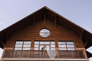 a newly married couple. the wind lifts a long white veil in summer. The bride and groom are hugging, a long veil is blowing in the wind. The newlyweds kiss on the balcony of the restaurant photo