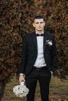 Portrait of a handsome young groom on an autumn day outdoors in an elegant suit. Outdoor photo. Handsome man in a business suit. photo