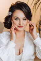 portrait of an incredibly beautiful girl bride in a white robe in the bedroom, the bride poses in the morning before the wedding ceremony. photo