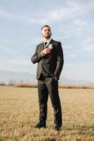 retrato de un hermoso joven novio en un otoño día al aire libre en un elegante traje. al aire libre foto. hermoso hombre en un negocio traje. foto