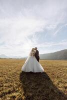 A young bride and groom tenderly embrace in the rays of the autumn sun. Tender and beautiful young girl bride. A man kisses his beloved. Against the background of a beautiful garden photo