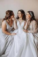 Portrait of the bride with her friends. Elegant and stylish bride with her friends in matching dresses in the room in the morning. Many beautiful girls in one photo. photo