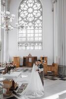 Lviv. This is a large Catholic church, the main attraction of the city. Interior of the bright church, panorama of large columns. The bride and groom at the wedding ceremony, photo from the back