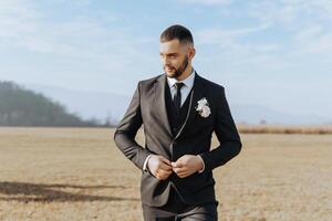 retrato de un hermoso joven novio en un otoño día al aire libre en un elegante traje. al aire libre foto. hermoso hombre en un negocio traje. foto