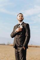 retrato de un hermoso joven novio en un otoño día al aire libre en un elegante traje. al aire libre foto. hermoso hombre en un negocio traje. foto