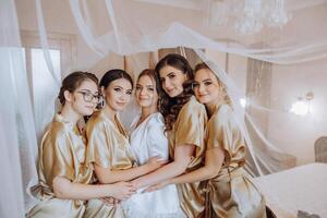 retrato de el novia con su amigos. elegante y elegante novia con su amigos en pareo vestidos en el habitación en el Mañana. muchos hermosa muchachas en uno foto. foto