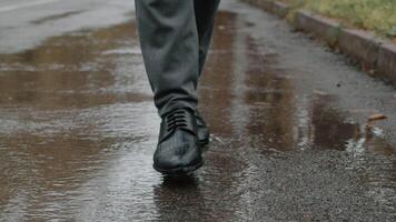 frente Visão do masculino pés dentro sapatos dançando em a molhado asfalto dentro a outono cidade parque dentro chuva fechar acima. homem dentro uma Boa humor caminhando Apesar de mau clima video