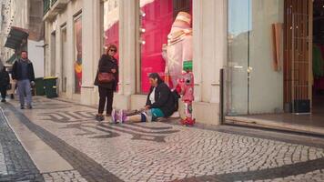 uma homem sentado em a calçada Próximo para uma loja video