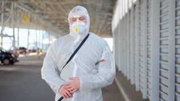 uma homem dentro uma protetora terno e mascarar com uma água pulverização ferramenta caminhando dentro a esvaziar estacionamento muitos video