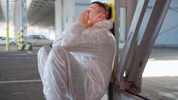 a man in a protective suit slowly sitting down in an empty parking lot video