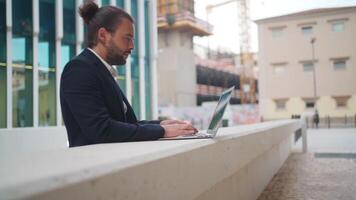 a man in a suit is working on his laptop n a business district outdoor video