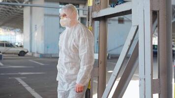 a man in a protective suit slowly sitting down in an empty parking lot video