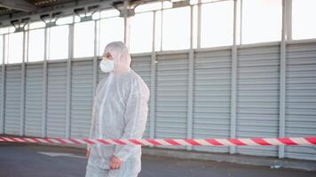 een persoon in een wit beschermend pak en masker is tonen X teken met zijn handen in voorkant van de rood lijn plakband video