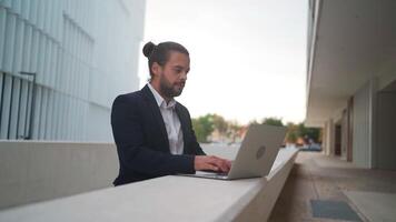 un hombre en un traje es trabajando en su ordenador portátil norte un negocio distrito al aire libre video
