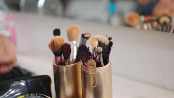 pan shoot of a set of make up brushes to a man with a beard and a gold hair piece standing in front of the mirror video