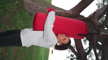 un mujer practicando boxeo con rojo boxeo bolso en el parque video