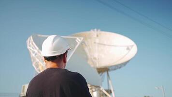ein Mann im ein schwer Hut Stehen im Vorderseite von Satellit Geschirr draussen video