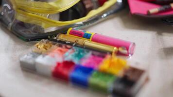 pan shot of colorful make up palette to a man with a beard and a gold hair piece applying make up in front of the mirror video