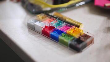 pan shot of colorful make up palette to a man with a beard and a gold hair piece applying make up in front of the mirror video