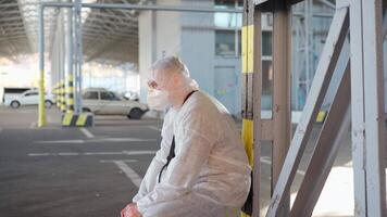 a man in a protective suit slowly sitting down in an empty parking lot video