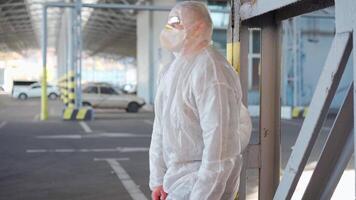 a man in a protective suit slowly sitting down in an empty parking lot video