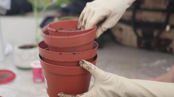 Gardner in white gloves stacking pots of different sizes in garden video