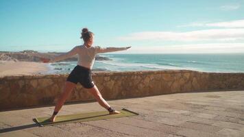 a woman is doing yoga on a yoga mat with ocean view in the background video