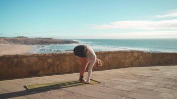 a woman is doing yoga on a yoga mat with ocean view in the background video