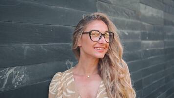 portrait de souriant femme dans branché lunettes penché sur gris mur video