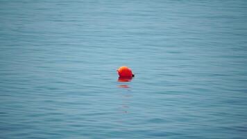 naranja boya flotante en el superficie de el mar ondas, concepto de humano vida seguridad. naranja la seguridad boyas en un cuerda flotante en el mar en un soleado día, cerca arriba. Esgrima de el nadando zona en playa. video