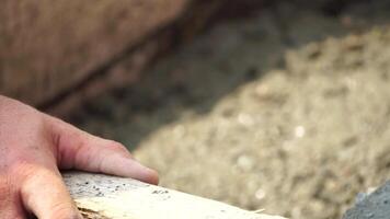 Construction, Worker Hands smooth wet cement in wooden frame at a construction site during daytime to ensure an even surface video