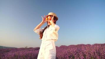 femme dans lavande champ - content Dame dans chapeau manger abricot sur ensoleillé jour, errant dans lavande champ, apprécier la nature. fille marcher au milieu de lavande fleurs, vaste champ pendant le coucher du soleil video