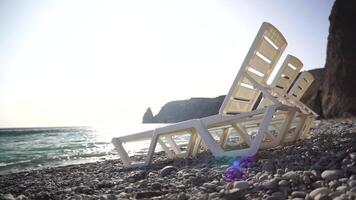 filas de vacío blanco el plastico silla y broncearse camas en playa cerca mar a puesta de sol. relajación zona para Relajado fuera en verano. playa sillas y Dom tumbonas al aire libre. verano vacaciones recurso concepto. video